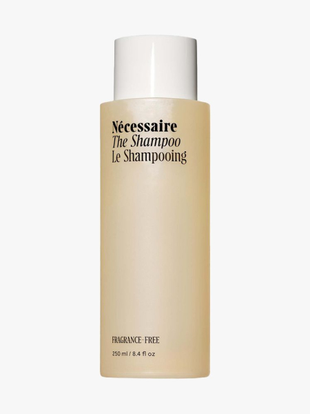Nécessaire The Shampoo beige bottle of shampoo with white cap on light gray background