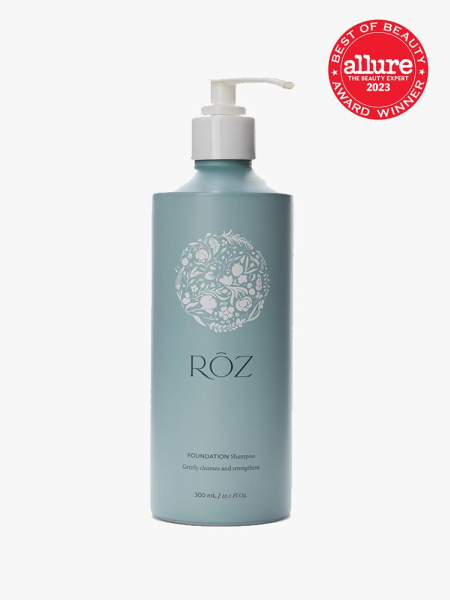 A light blue pump bottle with white pump cap of the Roz Foundation Shampoo on a light gray background